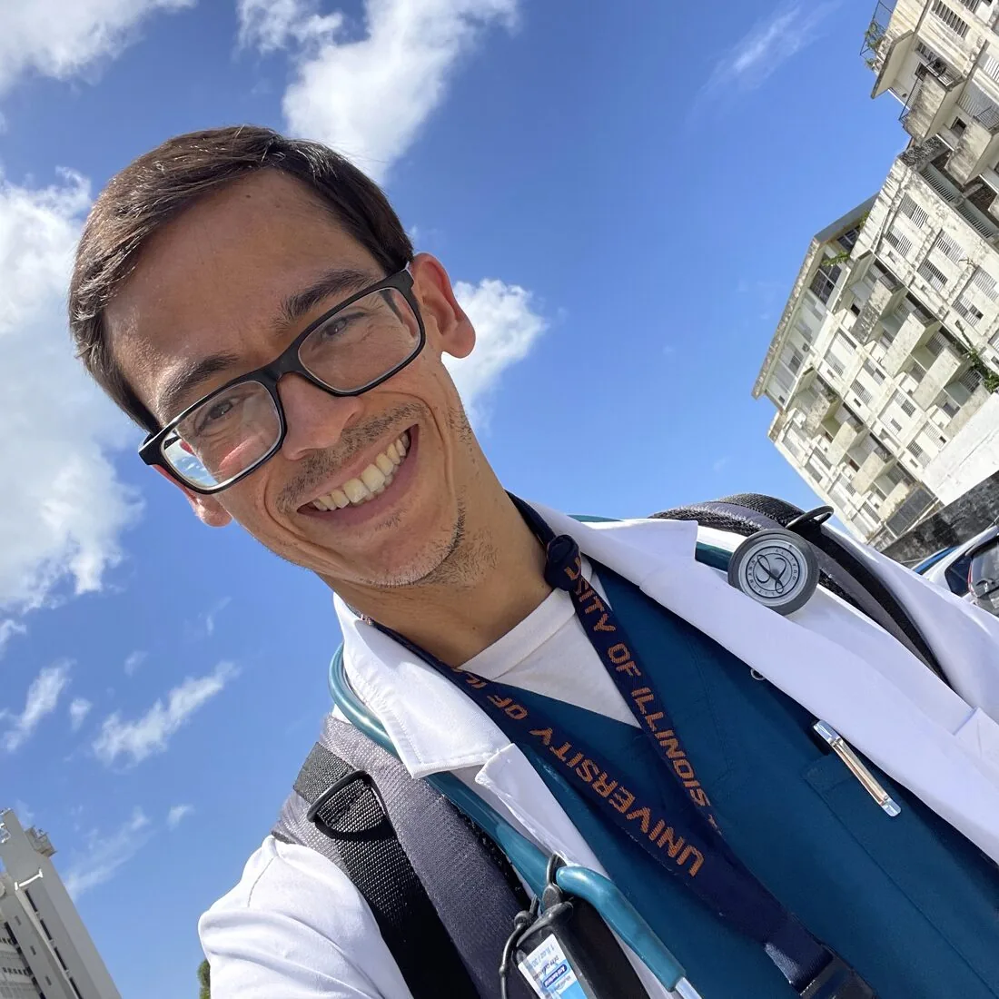 Dr. Giomarell Feliciano outdoors in his white coat and stethoscope, smiling